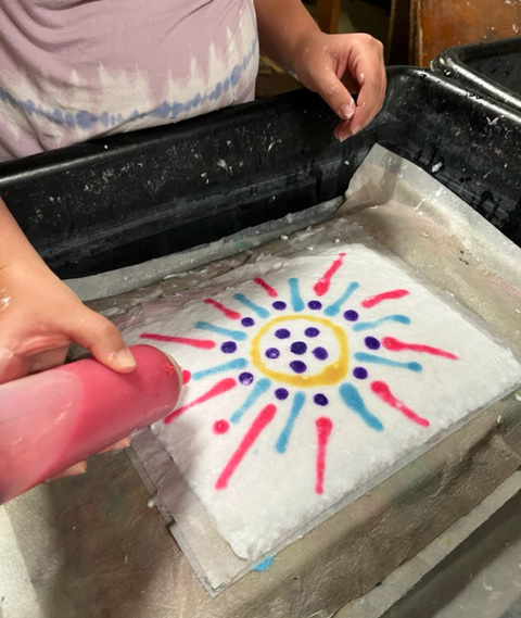 Gallery 1 - child decorating handmade paper with colored pulp